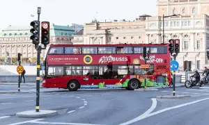 Röd dubbeldäckare för city sightseeing Stockholm passerar en korsning med trafikljus.