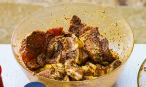 Karkówka w misce, gotowa do grillowania. Aromatyczna marynata do karkówki otula soczyste kawałki mięsa, zapowiadając pyszny posiłek.