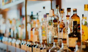 Rząd butelek z alkoholami, niektóre z etykietami wskazującymi, ile likier ma procent.