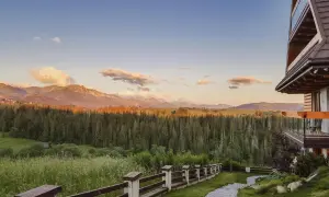Widok z hotelu Kopieniec Murzasichle na Tatry o zachodzie słońca. Drewniany domek, kamienna ścieżka i las.
