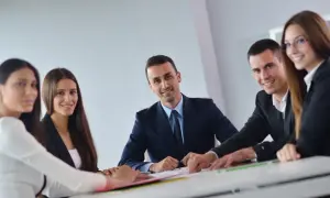 Uśmiechnięci ludzie na spotkaniu. Wszyscy ubrani są w eleganckie stroje, a atmosfera sugeruje owocną radę pedagogiczną.
