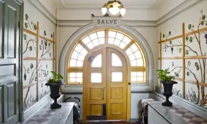 Entréhall med jugendstil hus-känsla. Dubbeldörrar med välvt fönster ovanför. Väggdekorationer med vinrankor.