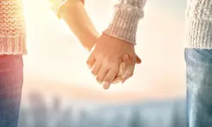 Manos entrelazadas bajo un sol cálido, un símbolo de una profunda **relación kármica** que trasciende el tiempo.