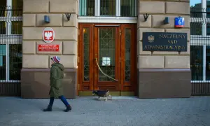 Przed budynkiem Naczelnego Sądu Administracyjnego przechadza się kobieta z psem.