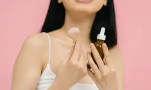 Kobieta z aparatem na zębach trzyma masażer do twarzy i serum. Czy wiesz, że retinol to witamina A, kluczowa dla zdrowej skóry?