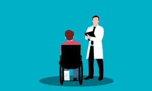 Medico con cartella parla con paziente su sedia a rotelle. Valutazione per la percentuale invalidità per esenzione ticket.