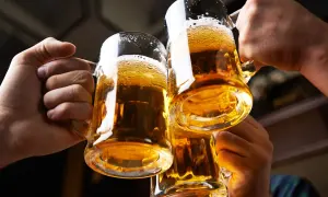 Trzy kufle ze złotym, orzeźwiającym piwem, gotowe do toastu. Piana lekko opada, a światło pięknie odbija się od szkła.