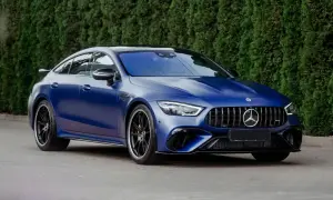 Niebieski matowy Mercedes-AMG GT 63 S z czarnymi felgami, zaparkowany przed żywopłotem.