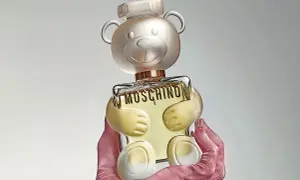 Różowe rękawiczki trzymają uroczy flakon perfum Moschino Toy 2 w kształcie misia.