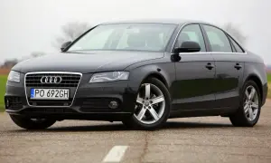 Czarne Audi A4 B8 z polskimi tablicami PO 692GH, z nowymi żarówkami w reflektorach, stoi na drodze.