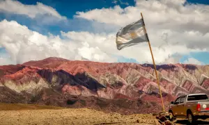 Wielobarwne góry w Argentynie, flaga powiewa na wietrze. Czy Argentyna jest bezpieczna? Tak, podróżowanie po Argentynie jest bezpieczne, zwłaszcza w takich malowniczych miejscach.