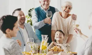 Radosny dzień rodziny przy stole. Dziadkowie, rodzice i dzieci śmieją się, wznosząc kieliszki z winem.