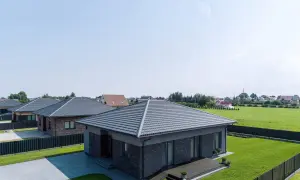 Nowoczesne domy z szarymi dachami, gdzie obróbka dachu wiatrownica zapewnia estetykę i ochronę przed wiatrem.