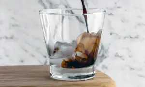 Kall kaffe hälls i ett glas med is.
