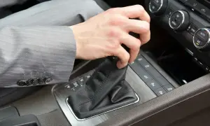 Pierwsza jazda automatem. Dłoń w garniturze zmienia bieg w samochodzie.