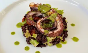 Delizioso polpo alla griglia su letto di riso venere, avocado e pomodorini, condito con salsa verde.