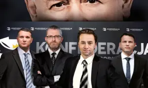 Konfederacja liderzy w garniturach na tle logo partii. W górnej części kadru widać fragment twarzy starszego mężczyzny.
