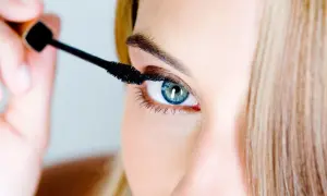 Une femme applique du mascara. Pour savoir comment enlever du mascara waterproof, il faut un bon démaquillant.