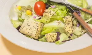 Salade fraîche avec cubes de tofu aux graines, maïs, tomate et graines de courge. Parfait pour savoir que manger après le sport.