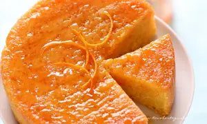 Una deliziosa torta all'arancia, lucida e profumata, con una fetta tagliata. Perfetta per una pausa golosa.