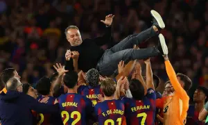 Piłkarze FC Barcelona 22/23 unoszą trenera Xaviego w geście radości po wygranym meczu.