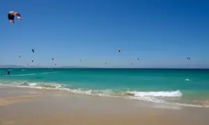 El levante en Tarifa impulsa a numerosos kitesurfistas sobre aguas turquesas. Un día perfecto para disfrutar del mar y el viento.