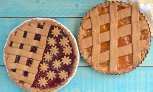 Due crostate senza uova, una con marmellata di frutti rossi e decorazioni a fiore, l'altra con marmellata di albicocche.