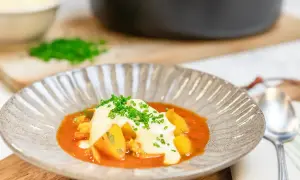 En vällagad fisksoppa med saffran, toppad med krutonger och färska örter. Serveras i en vacker skål med en sked bredvid.