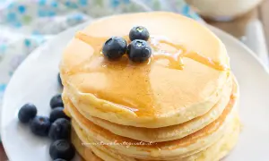 Pancakes soffici con albumi, guarniti con mirtilli freschi e sciroppo d'acero.