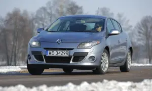 Srebrny Renault Megane 3 z włączonymi żarówkami przód, na drodze zimą.