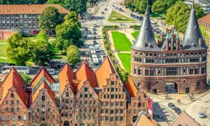 Blick auf Holstentor und historische Backsteinhäuser in Lübeck, ein Wahrzeichen vieler historischer Orte Deutschlands.