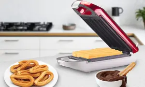 Máquina para hacer churros abierta con churros dentro, plato de churros y tazón de chocolate.