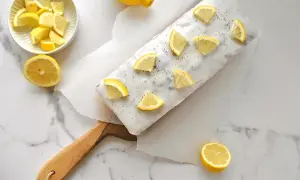 Ein köstlicher zitronen mohn kuchen, verziert mit frischen Zitronenspalten und Mohn. Daneben eine Schale mit Zitronenstücken und ganze Zitronen.