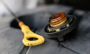 Żółta miarka z napisem "ENG OIL" i zakręcona nakrętka z widocznym olejem. Sprawdzanie, ile oleju do silnika, to podstawa.