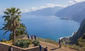 Blick auf Ribeira da Janela mit Palmen und dem tiefblauen Meer. Touristen genießen die Aussicht auf die Küste und die Berge.