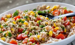 Insalata di farro colorata con pomodorini, mais e prezzemolo fresco, servita in una ciotola bianca.