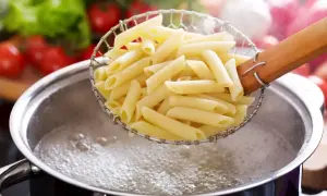 Penne w cedzaku nad garnkiem z wrzącą wodą. Idealny sposób, jak ugotować makaron, by był al dente.