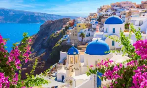 Vue panoramique de Oia, Santorin, l'une des plus belles îles grecques, avec ses dômes bleus iconiques et ses bougainvilliers roses éclatants.
