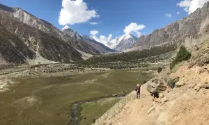 Wanderer auf einem Pfad im Rupal-Tal, umgeben von majestätischen Bergen und grünen Tälern.