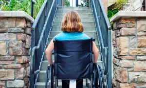 Ragazza in carrozzina affronta una scalinata, un aiuto per l'accessibilità come previsto dalla legge 104.