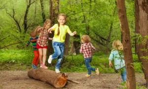 Niños jugando en un tronco, practicando el equilibrio. ¡Una escena de diversión y desarrollo para el equilibrio en niños de 1 a 2 años!