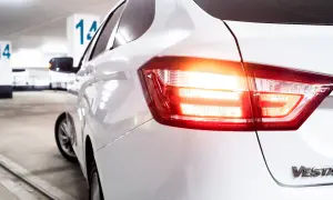 Vue arrière d'une voiture blanche dans un parking. Les feux de recul obligatoires sont allumés, signalant un départ imminent.