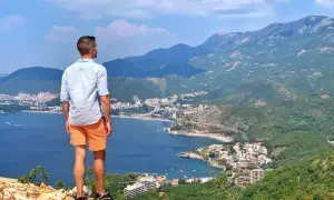 Mężczyzna podziwia widok na wybrzeże Czarnogóry. Warto uważać na strome ścieżki podczas wędrówek po górach.