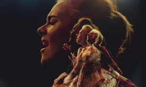 Adele śpiewa "Send My Love" w wielokrotnej ekspozycji, jej twarz i postać w sukni rozmywają się w mroku.