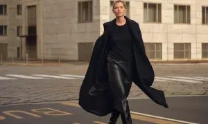 Elegancka kobieta w czarnej, skórzanej spódnicy i płaszczu. Idealna stylizacja, która pokazuje, jaka bluzka do skórzanej spódnicy pasuje najlepiej.