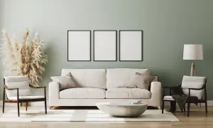 Miętowa ściana idealnie komponuje się z białymi meblami, tworząc przytulną aranżację. Sofa, fotele i stolik kawowy w jasnych barwach.