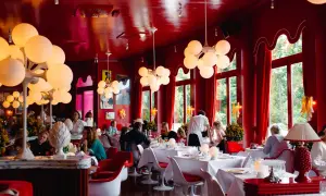 Ein lebhaftes **Cafe Berlin Mitte** mit roten Wänden, auffälligen Kugelleuchten und Gästen, die an weiß gedeckten Tischen sitzen.