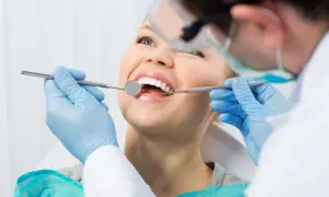 Uśmiechnięta pacjentka u dentysty. Zastanawiasz się nad lakowaniem zębów? Skutki uboczne są rzadkie, ale warto wiedzieć.
