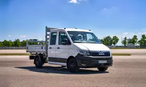 Camionnette MAN blanche avec plateau, prête pour le **c tuning** et le travail. Ciel bleu et verdure en arrière-plan.