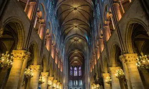 Intérieur de Notre Dame de Paris, avec ses voûtes gothiques, vitraux colorés et chandeliers. On se demande si peut on visiter Notre Dame de Paris.
